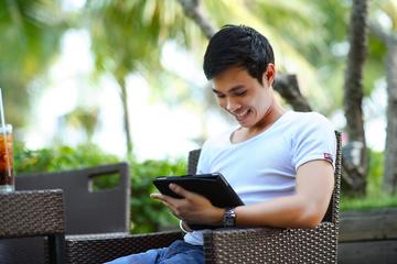 man in white shirt using tablet computer outdoors